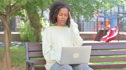 Woman Works on Laptop Outdoors on Park Bench