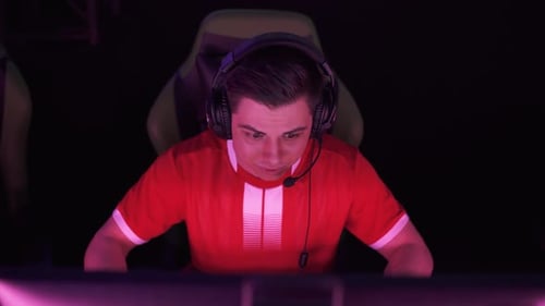 киберспортсмен в наушниках сосредоточенно играет