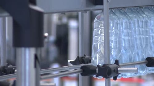 New plastic bottles on the conveyor belt of a drinking water plant. Clear water from a deep well in