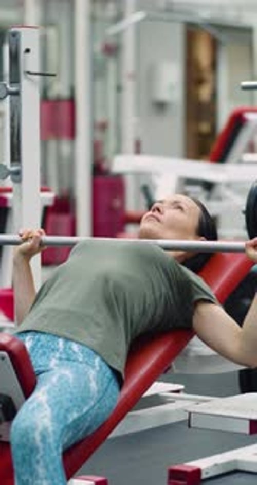 Woman Doing Bench Press on Incline at Gym