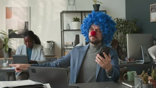 Funny Businessman Dressed as Clown Talking on Phone at Office Desk