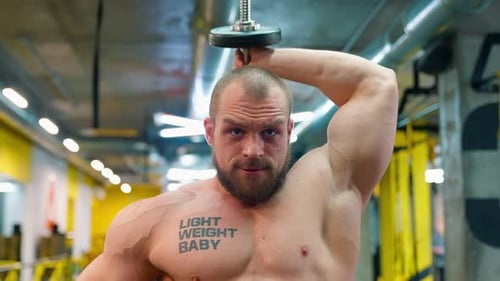 Muscular Man Lifting Dumbbell in Gym