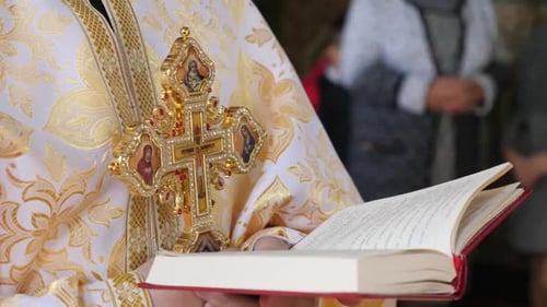 S146. The priest preaches holding a bible and a cross.