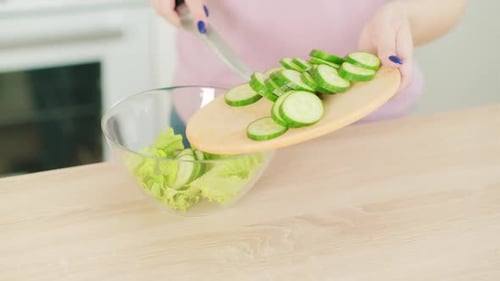 Preparing Healthy Green Salad with Cucumber in Kitchen