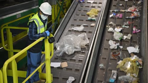 Recycling Plant Worker Observing Conveyor Belt