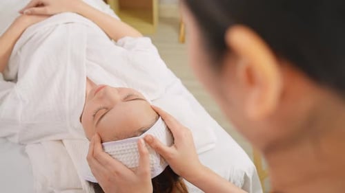 Asiatische junge Frau wird im Beauty Spa mit Kopf- und Gesichtsmassage behandelt.