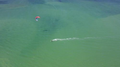 Kite / Wind Surfer Soars across Turquoise / Blue / Green Ocean Waters off the coast of Fuzeta,