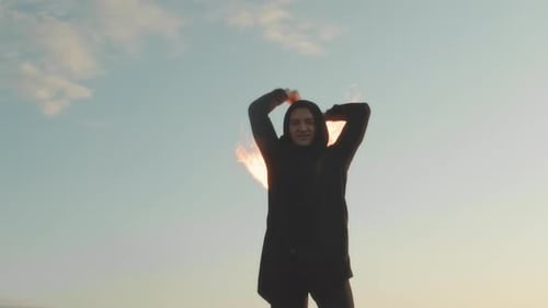 Skilled Fire Dancer Twirling Torches at Sunset