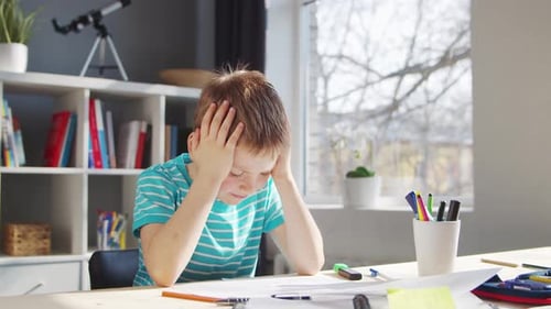 Boy is Doing His Homework at the Table Cute Child is Learning at Home with the Help of Textbooks and