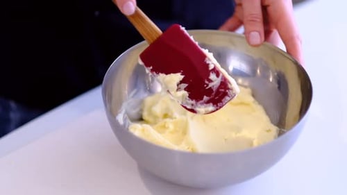 Person Mixing Creamy Ingredients in Bowl with Spatula