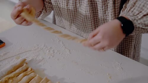 Junge Frau formt schwedischen Kardamom und macht zu Hause in der Küche Brötchen. Hausgemachtes Gebäck hautnah