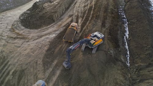 Excavator Filling Dump Truck on Construction Site