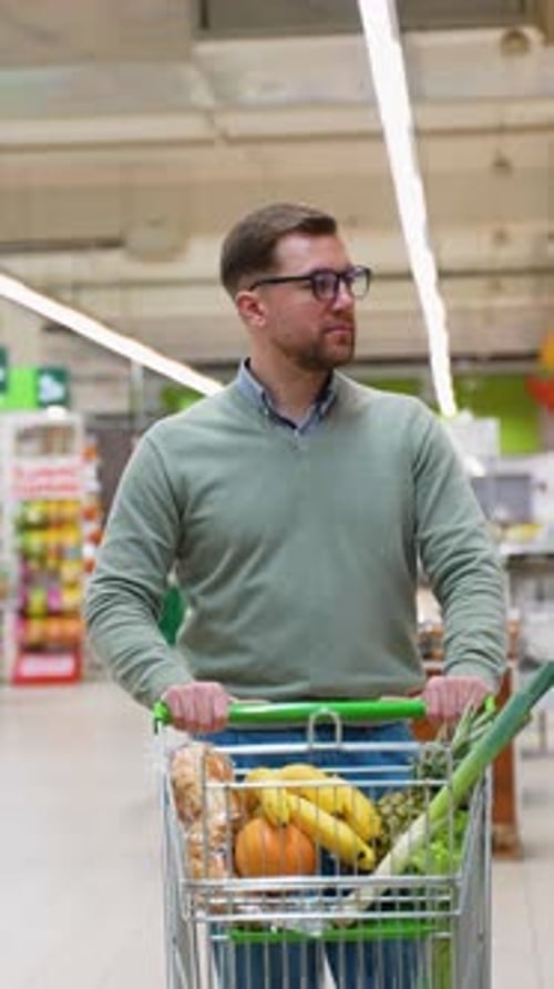 Man Shopping in Supermarket with a Full Grocery Cart