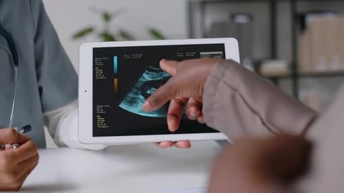 Mains d'une obstétricienne et d'une patiente enceinte discutant de l'échographie du fœtus