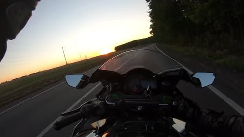 Motorcycle Rider Rides in Rural Road at Sunset Time The Viewpoint of Motorcyclist Driving Motorbike