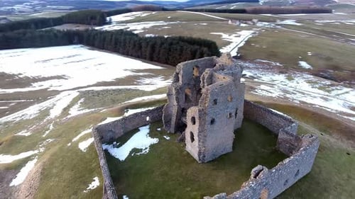 Aerial view over snowy countryside ancient medieval castle ruins & stone wall architecture. Orbit ri