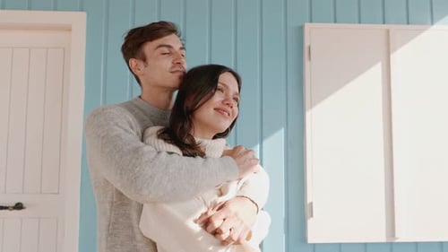 Casal afetuoso se abraçando em um ambiente aconchegante antes de persianas azuis