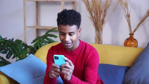 Young Man Using Phone on Couch Indoors