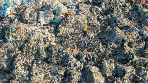 Drone view of huge heaps of pressed garbage at waste sorting plant. Slow motion