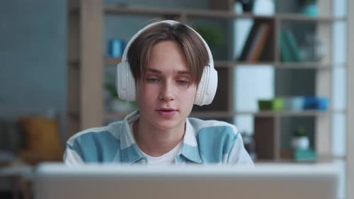 Teen Student using Laptop with Headphones Indoors