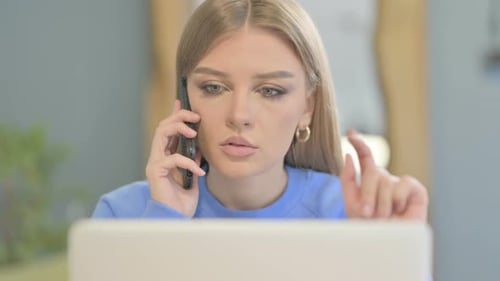 Close Up of Woman Talking on Phone while using Laptop