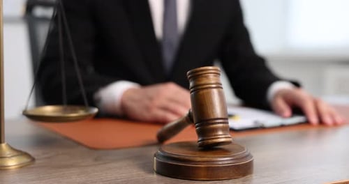 Juez golpeando un mazo contra un escritorio de madera en el interior, primer plano