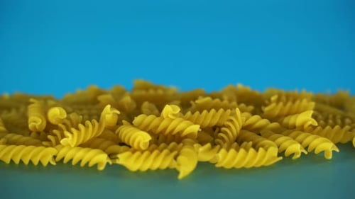 Fond alimentaire : pâtes, fusilli sur fond bleu