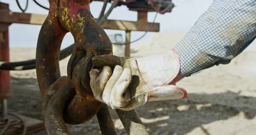 Arbeiterhand mit Schutzhandschuh, der die große Metallmutter festzieht.