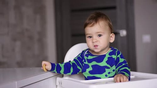 Adorable Infant Eating a Snack in Highchair
