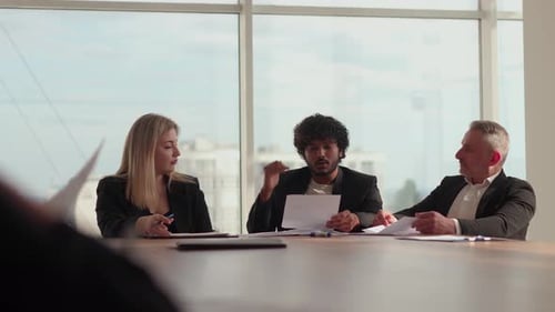 A Team of Businessmen Sitting in the Office Against the Background of a Window is Discussing