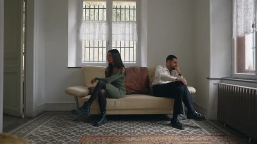 Couple in crisis. Young man and woman ignoring each other seated on couch doing silent treatment. Pe