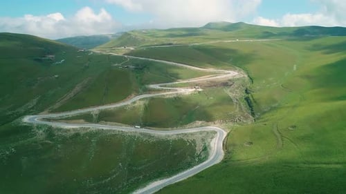 Aerial Over Winding Asphalt Road Among Mountains Covered with Green Grass in Highlands of Caucasus