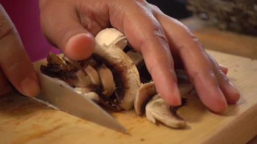 Person Prepares Fresh Mushrooms on Cutting Board