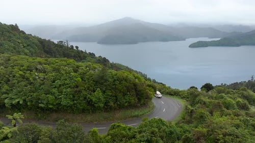 Motorhome driving in remote road of Marlborough Sounds misty valley. Aerial