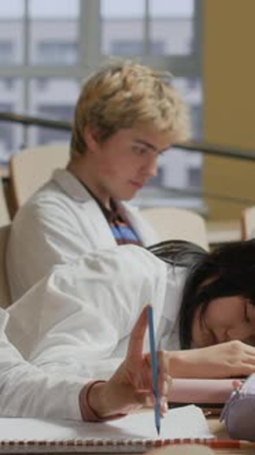 Tired Female Medical Student Lying on Desk in Lecture Class at College
