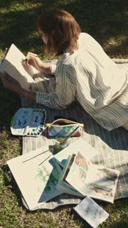 An Inspired Woman Lying on the Blanket in Park in