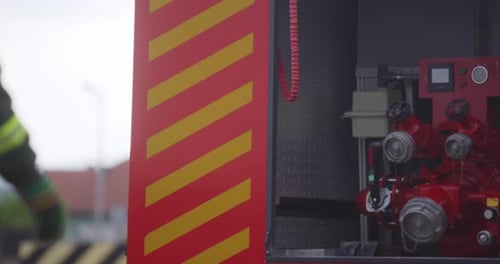 Firefighters and Equipment at Fire Truck's Open Compartment