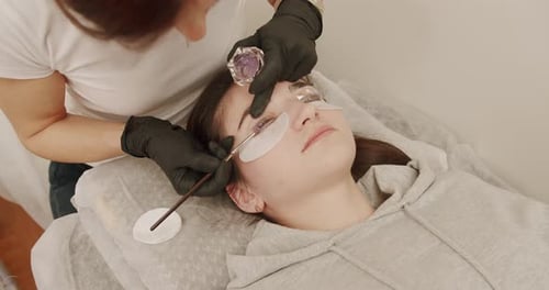 Master and Client in Beauty Salon Professional Stylist Lengthening Female Lashes