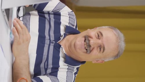 Vertical video of Home office worker old man smiles at camera.