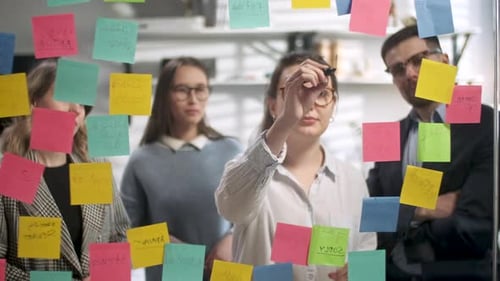 Brainstorming Team Write on Sticky Notes in Office