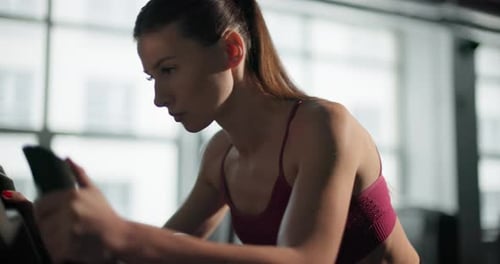 A Young Beautiful Brunette Girl in Sportswear Exercises on a Simulator in the Gym Doing Cardio