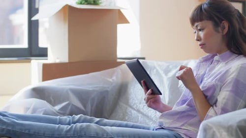 Woman Relaxes with Tablet Amidst Moving Boxes