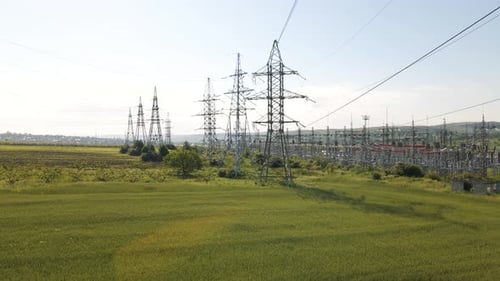 Aerial Cinematic Clip Drone Flies Rising Over a Wheat Field and High Voltage Electric Towers