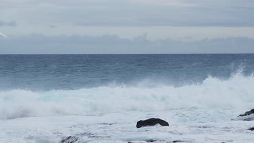 Powerful ocean waves crashing against dark coastal rocks