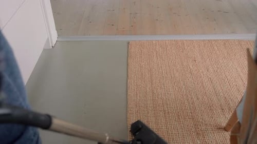 Person Vacuuming Woven Rug in Home Interior