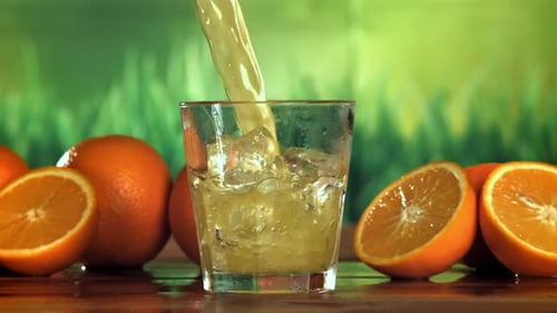 Orange Juice Pouring Over Ice in Glass