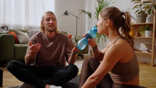 Young Couple Hydrating and Chatting After Workout