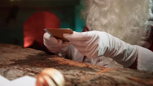 Santa Claus Opens Christmas Cards by Fireplace