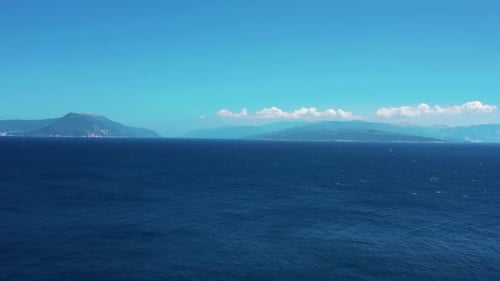 Serene Sea Landscape with Distant Mountains Under Blue Sky