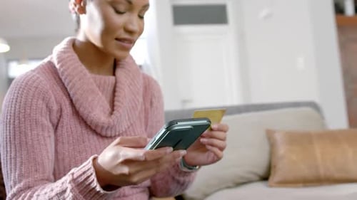 Woman Using Phone and Credit Card at Home